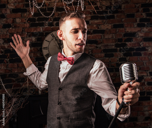 man in suit posing with condenser microphone. Emotional young man with a microphone in his hands