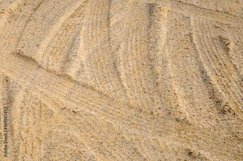 Light sand trampled by tire tracks, may be used as background or texture