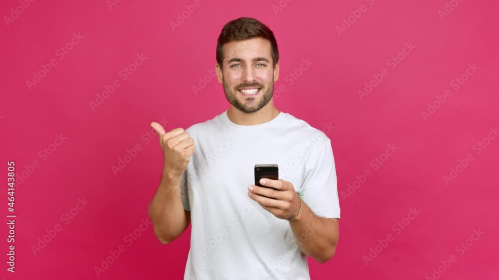 Handsome man using mobile phone and pointing side over isolated background Handsome man using mobile phone and pointing side over isolated background