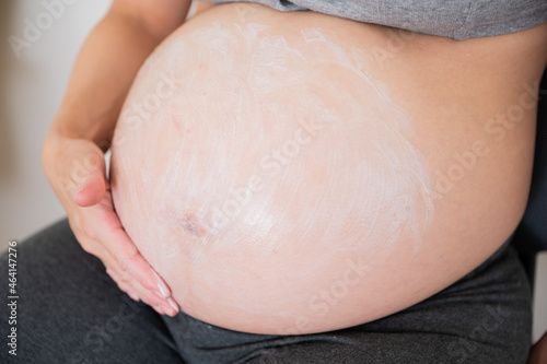 applying cream on the belly of asian pregnant women