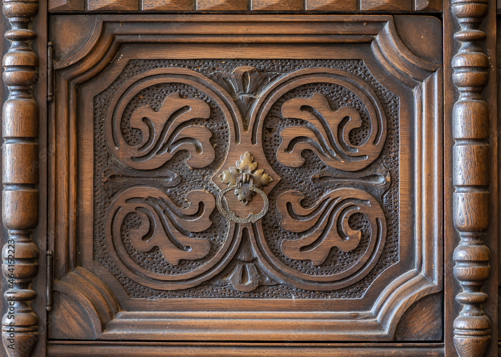 Old furniture piece from close, featuring carved pattern and a handle, background or backdrop copy-space