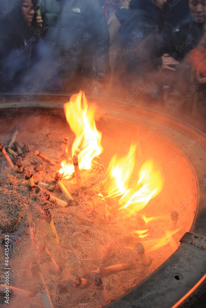 Naklejka premium 香炉の中で、めらめらと炎を上げている線香の束