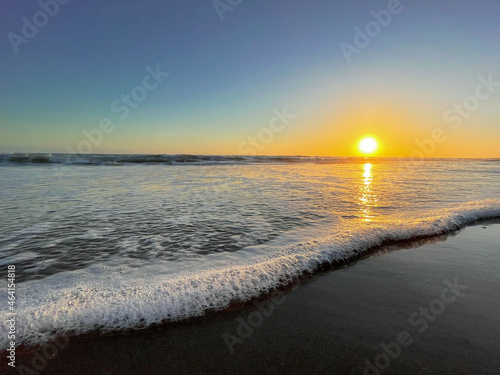 Low angle shot of a wave gently washing over the sandy beach at Chrystal Cove State Park in Orange County California at sunset