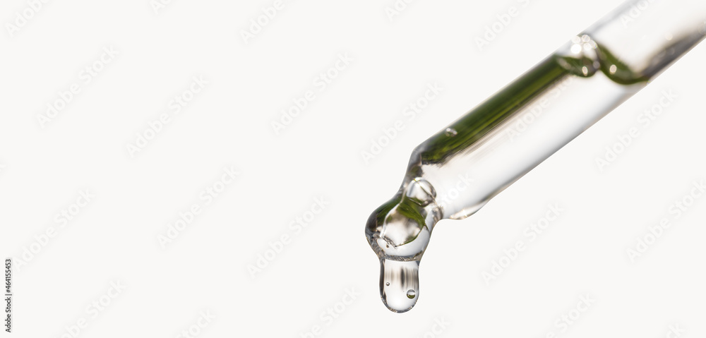 Cosmetic pipette with essential oil dropping, serum with peptides, hyaluronic acid on white background. Closeup of blue dropper, falling drop close up. Self care concept. Beauty skin care product.