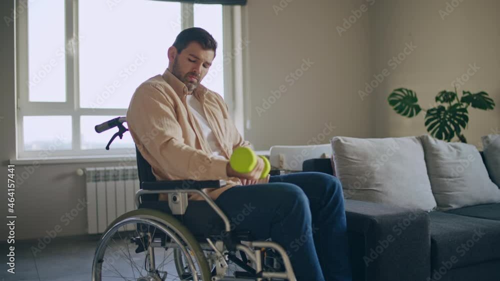 Young man with reduced mobility doing exercises with dumbbell, rehabilitation Young man with reduced mobility doing exercises with dumbbell, rehabilitation