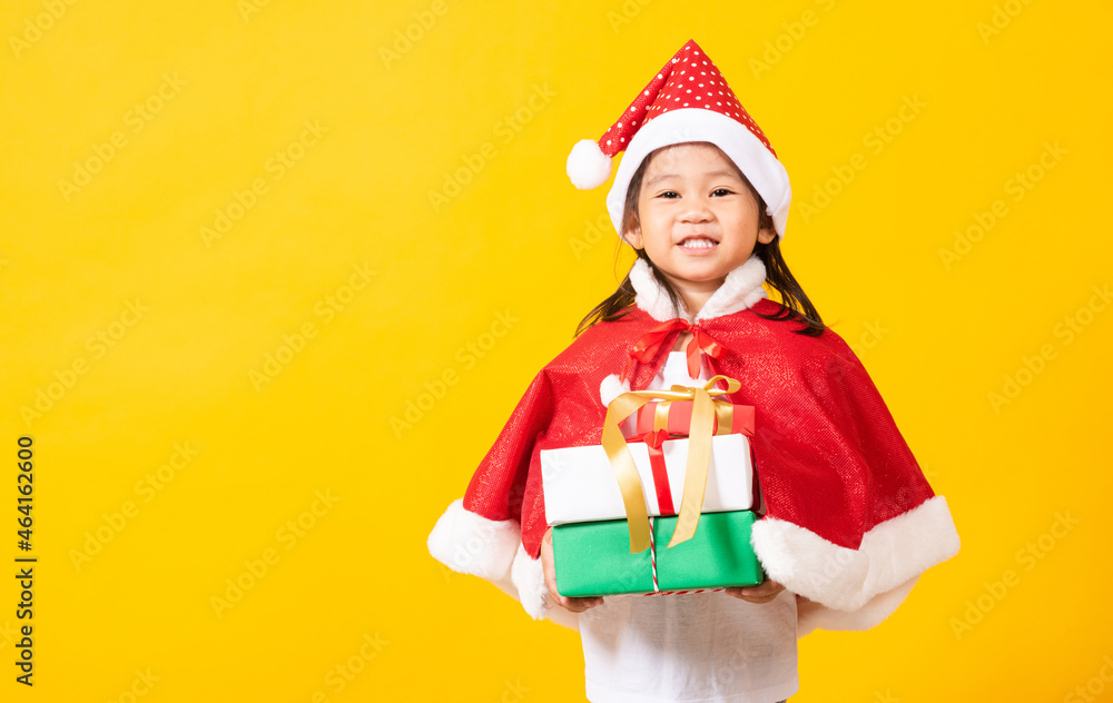 Asian little cute girl smile and excited, Kid dressed in red Santa Claus hat hold gift box on hands concept of holiday Christmas Xmas day or Happy new year, studio shot isolated on yellow background Asian little cute girl smile and excited, Kid dressed in red Santa Claus hat hold gift box on hands concept of holiday Christmas Xmas day or Happy new year, studio shot isolated on yellow background