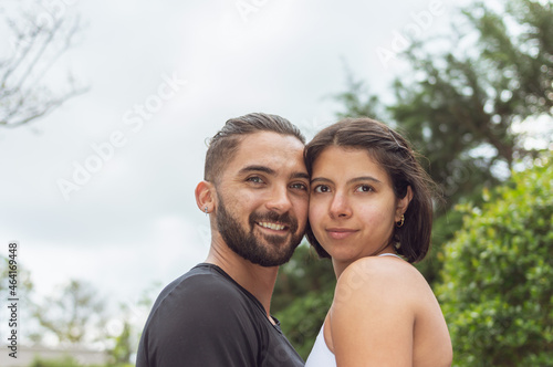 A loving couple touching each other looking at the camera outdoors