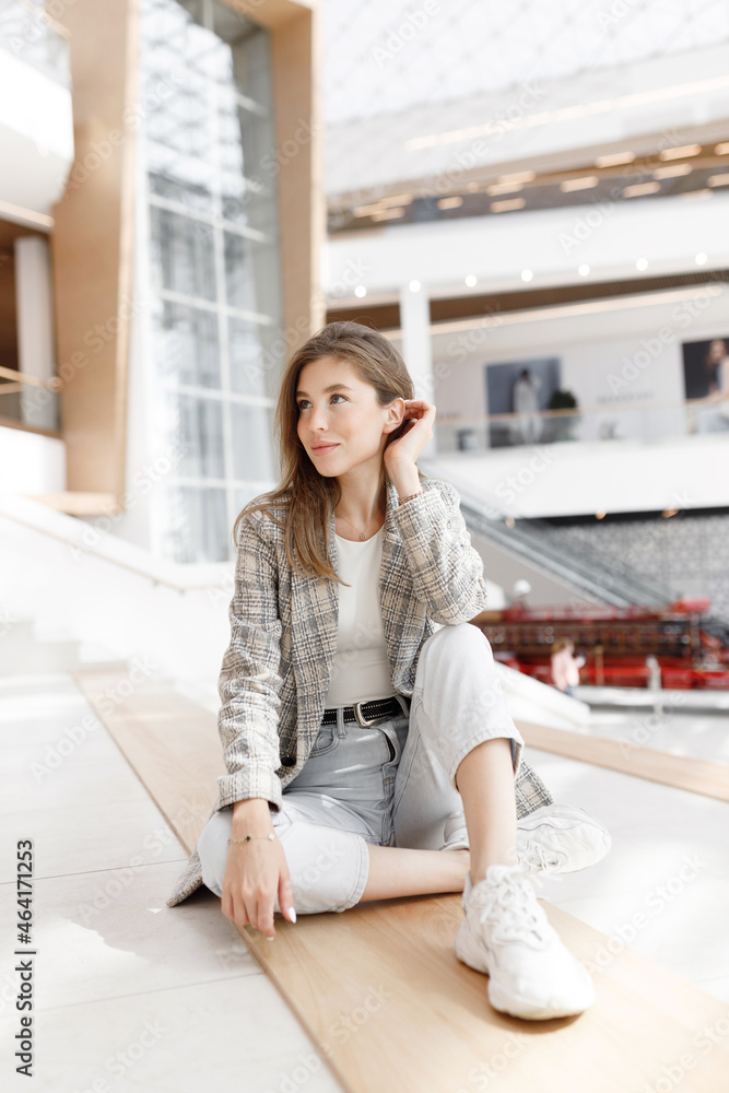 A woman is sitting in a shopping mall, laughing and smiling. Young blogger girl, close-up portrait with natural makeup. A woman is sitting in a shopping mall, laughing and smiling. Young blogger girl, close-up portrait with natural makeup.