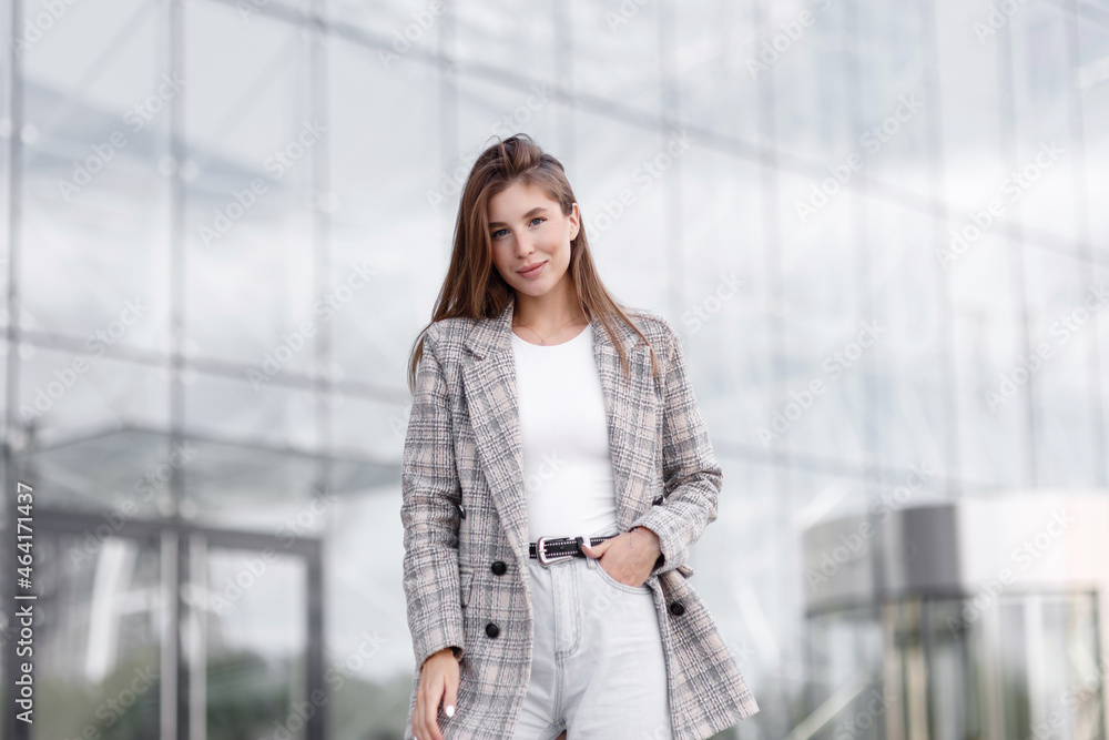 Fototapeta premium A modern business woman in an office with a neutral background. A young girl, a break at work, a work situation.