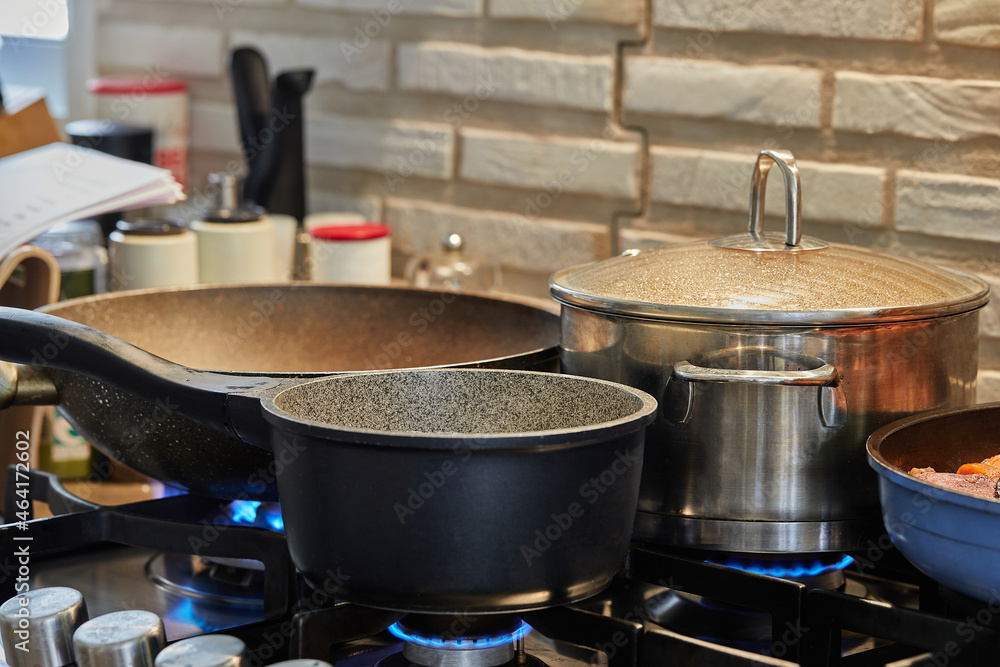 Preparing food in frying pan and casseroles on the gas stove in the kitchen Preparing food in frying pan and casseroles on the gas stove in the kitchen