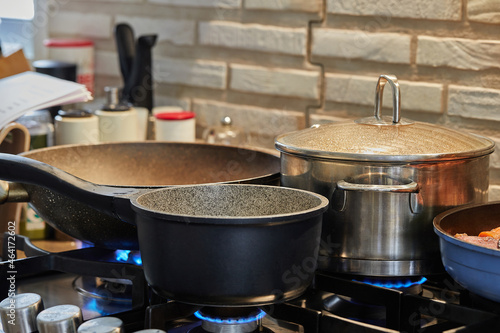 Preparing food in frying pan and casseroles on the gas stove in the kitchen
