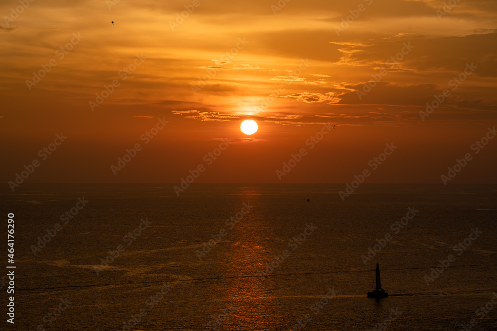 Sunset on the sea and through the clouds over. Tranquil seascape with the horizonal skyline.