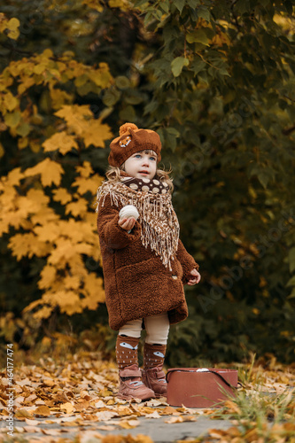 A dreamy little girl in a brown beret and autumn clothes on an autumn background. A smiling child is playing in the autumn park.