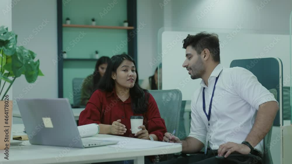Diverse indian and caucasian colleagues discuss financial data analyzing marketing result in report using laptop having business conversation help coworker with corporate project sit at office desk. Diverse indian and caucasian colleagues discuss financial data analyzing marketing result in report using laptop having business conversation help coworker with corporate project sit at office desk.