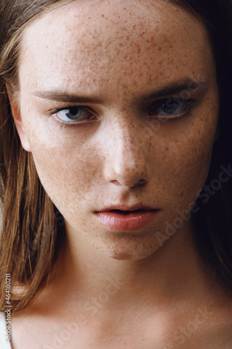 Portrait of a beautiful girl with long hair, perfect skin and freckles looking in camera © moravska