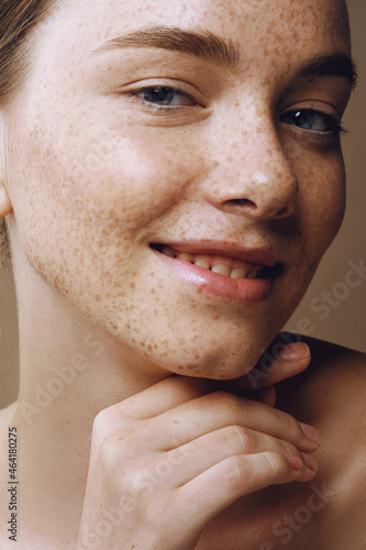 Young smiling woman with perfect freckled skin and nude makeup