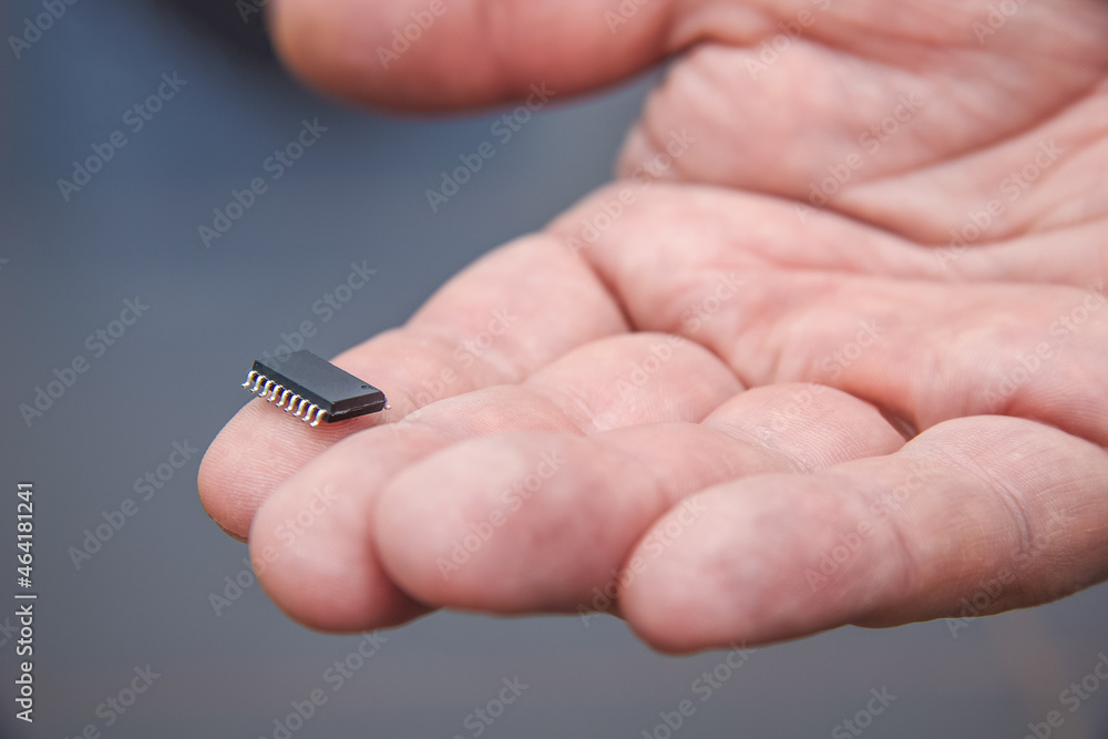 Hand holds chip compenent. Embedding the chip under human skin