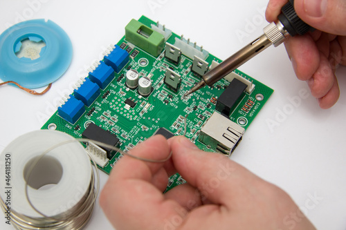 Billede på lærred Male hands solder components onto a printed circuit board using copper and a soldering iron