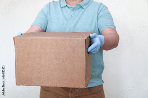 Parcel delivery. Courier in gloves and a mask with a box for a customer. A man with a parcel in his hands.
