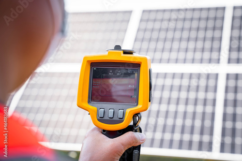 The technician takes the Thermoscan(thermal image camera) scan to the solar panel to check the hot spots in the cell, Concept to use technology to check the damage in the Solar plant photo