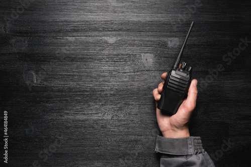 A worker with a walkie talkie radio station in the hand on the black flat lay background with copy space. photo