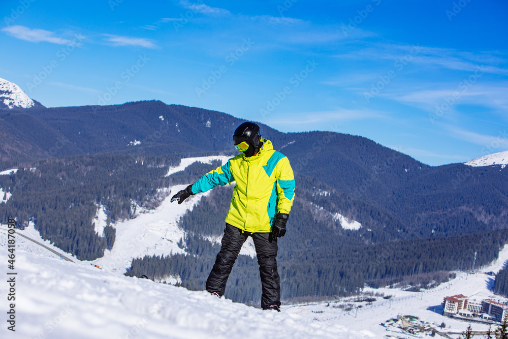 man on the top of the hill with snowboard in sunny day