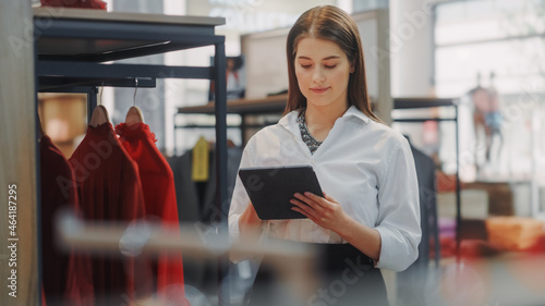 Clothing Store: Female Visual Merchandising Specialist Uses Tablet Computer To Create Stylish Collection. Fashion Shop Sales Retail Manager Checks Stock. Small Business Owner Orders Merchandise