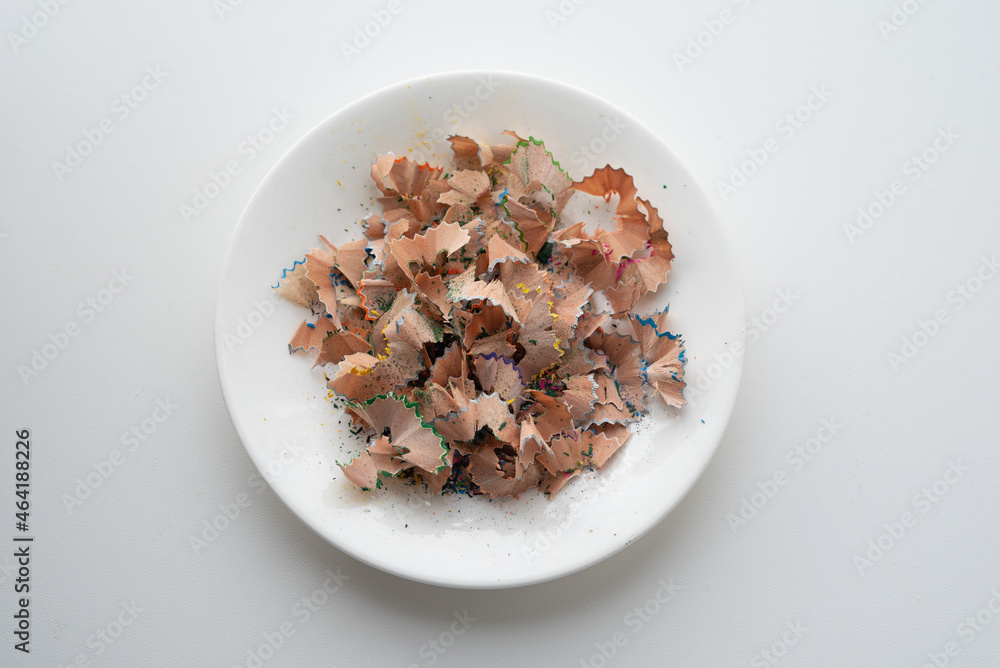 Pile of pencil husk after sharpening in a white plate on white background Pile of pencil husk after sharpening in a white plate on white background