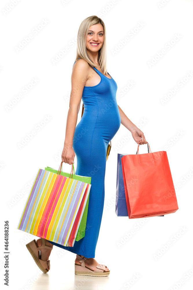 Young happy pregnant woman in long blue dress posing with a shopping