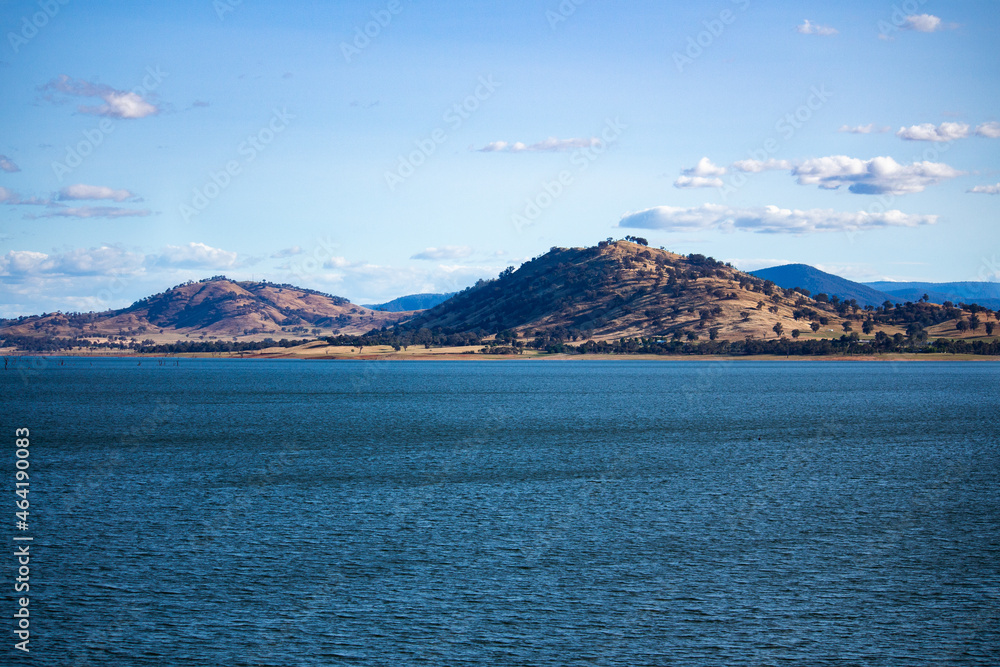 Blue waters of the Hume Dam across Murray River, New South Wales, Australia with sun shining upon hills in background