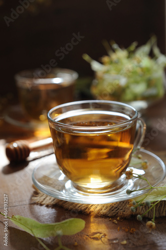 Cups of linden tea on wooden background in sunshine light