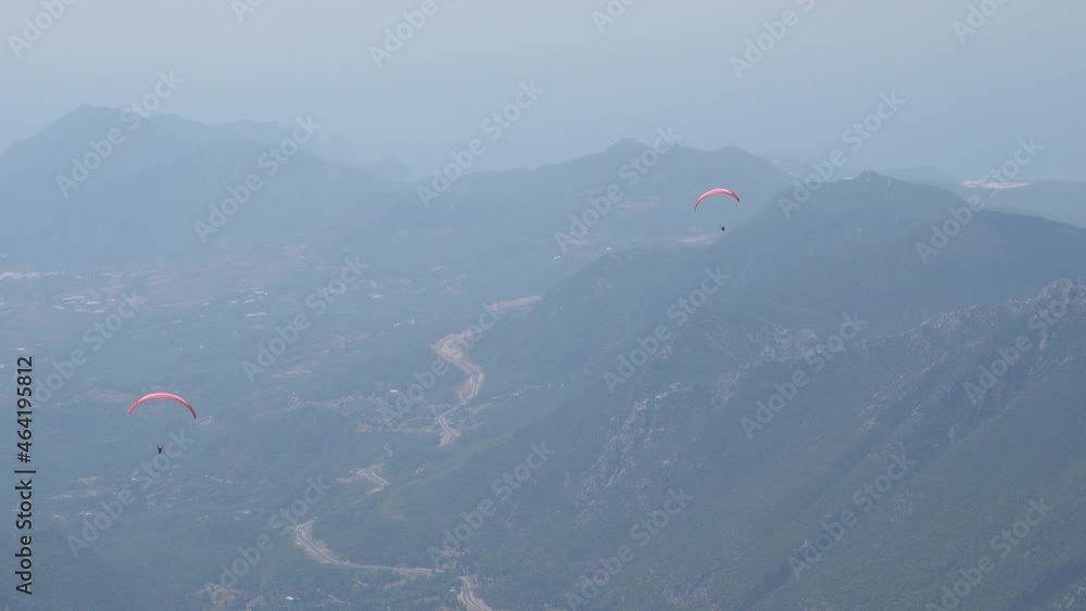 Paragliders fly over mountain top in epic scenery. Parachutes or paragliding experience. Adrenaline and extreme sport. Beautiful tranquil and calm time in nature Paragliders fly over mountain top in epic scenery. Parachutes or paragliding experience. Adrenaline and extreme sport. Beautiful tranquil and calm time in nature