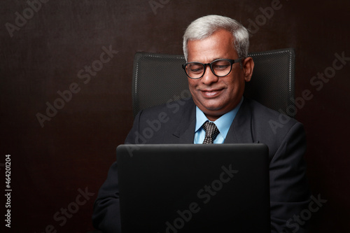 Portrait of a smiling businessman of Indian ethnicity looking at his laptop computer
