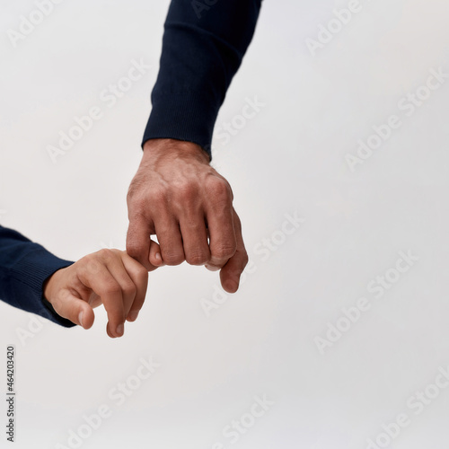 Close up crop of father and son hold hands