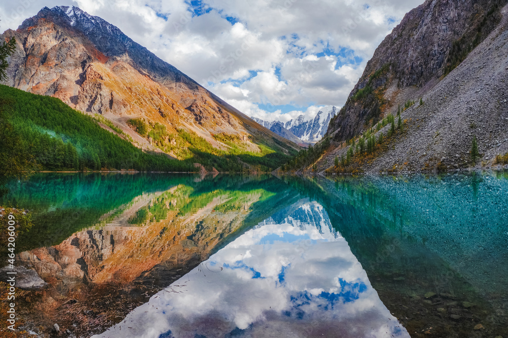 Picturesque mountain lake in the dramatic day, Altai. Beautiful reflection of mountains, sky and white clouds. Picturesque mountain lake in the dramatic day, Altai. Beautiful reflection of mountains, sky and white clouds.