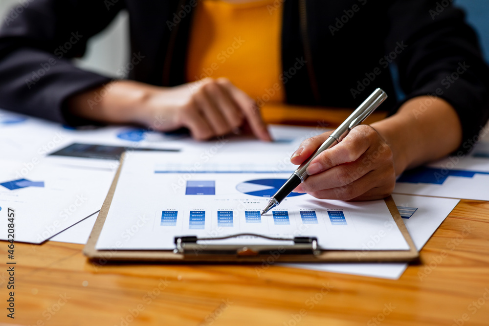 Fototapeta premium Close up Business woman using calculator and laptop for do math finance on wooden desk, tax, accounting, statistics and analytical research report concept