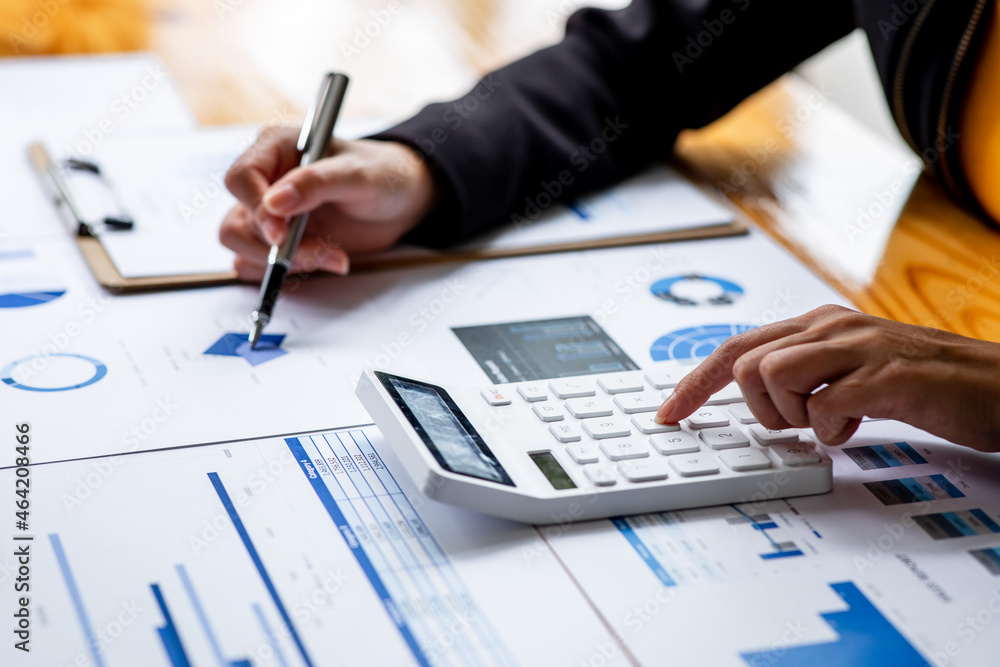 Close up Business woman using calculator and laptop for do math finance on wooden desk, tax, accounting, statistics and analytical research report concept Close up Business woman using calculator and laptop for do math finance on wooden desk, tax, accounting, statistics and analytical research report concept