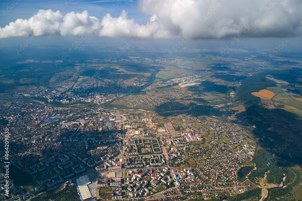 Aerial view from airplane window at high altitude of distant city covered with puffy cumulus clouds forming before rainstorm. Aerial view from airplane window at high altitude of distant city covered with puffy cumulus clouds forming before rainstorm.