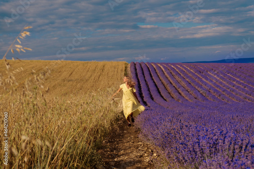 meeting of two worlds: a girl in a yellow dress between a wheat and lavender field