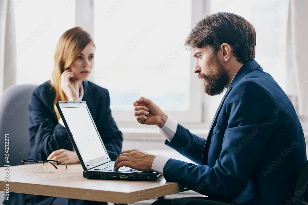 business man and woman in the office in front of a laptop career network officials business man and woman in the office in front of a laptop career network officials
