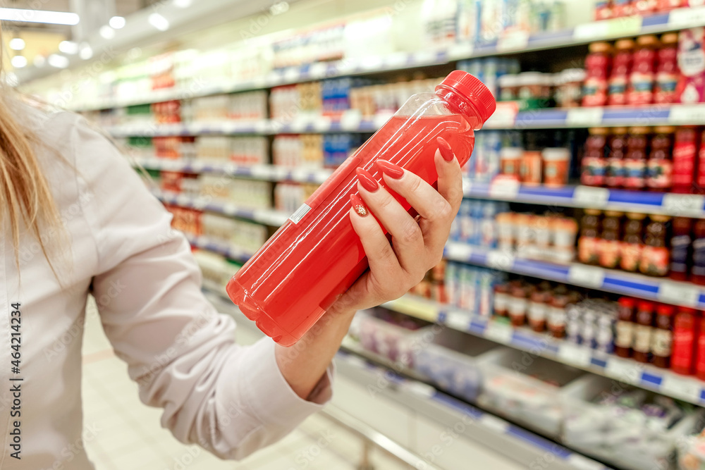 Woman holding bottle of red juice in supermarket