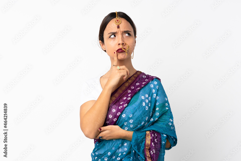 Young indian woman isolated on white background having doubts while looking up