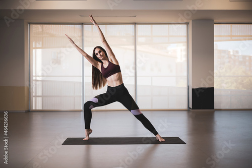 a pretty young girl practicing yoga in a gym room.