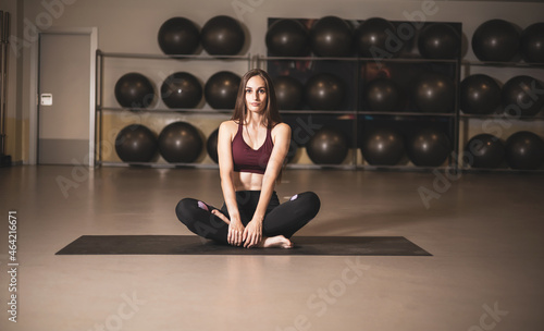 a pretty young girl practicing yoga in a gym room. photo