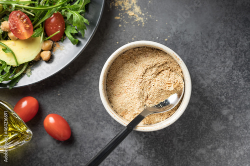 Bild auf Leinwand Nutritional yeast flakes in ceramic bowl on dark background