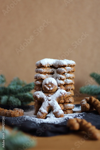 Many snowy Christmas cookies in the form of gingerbread men and canes in brown background.