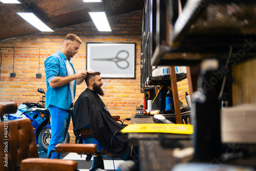 A male hairdresser cuts a customer's hair in his salon