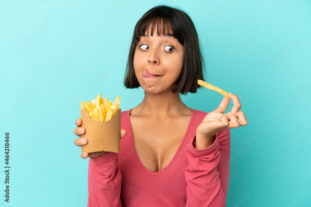 Young brunette woman holding fried chips over isolated blue background Young brunette woman holding fried chips over isolated blue background