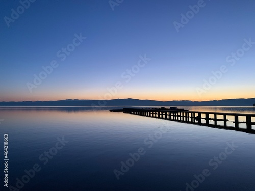 Silhouette of a long pier at the surface of the lake  sunset time  natural colors