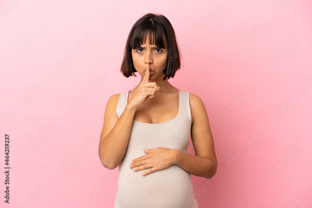 Young pregnant woman over isolated pink background showing a sign of silence gesture putting finger in mouth Young pregnant woman over isolated pink background showing a sign of silence gesture putting finger in mouth
